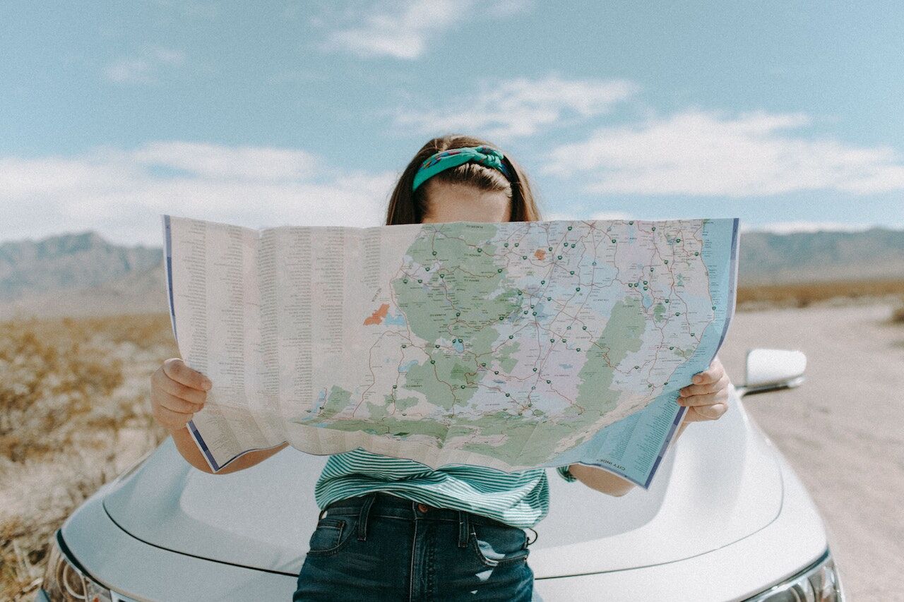 A lady viewing a physical map to help navigate her location.
