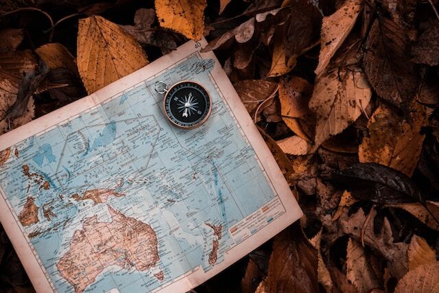 A compass resting on a world atlas.