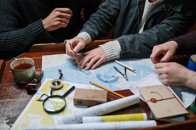 A group of people drawing a US map with pencils, rulers, and other drawing materials.